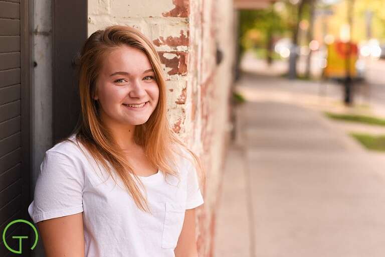 A high school senior casually poses in Ann Arbor's Kerrytown during her senior portrait session