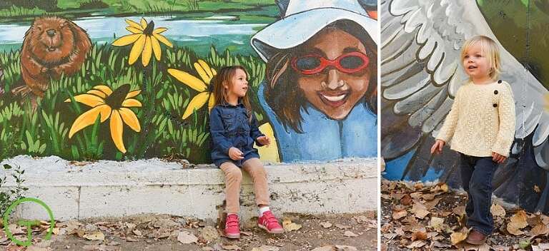 Two young sisters pose near a beautiful mural in Ypsilanti