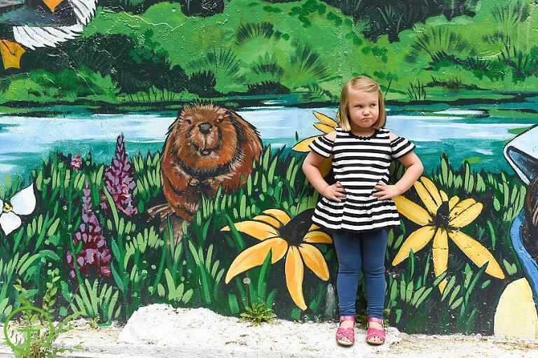 A child poses near a colorful mural for her ypsilanti depot town portrait session