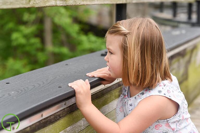 a child looks out at the huron river in ypsilanti during her portrait session