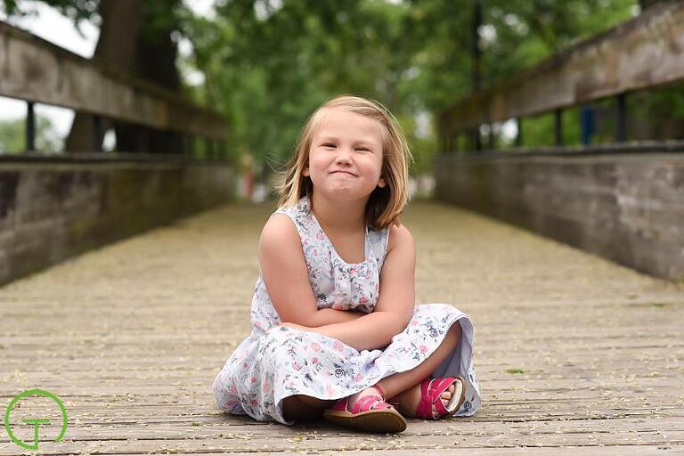 a child is all smiles on Ypsilanti's historic bridge over the huron river for her portrait session