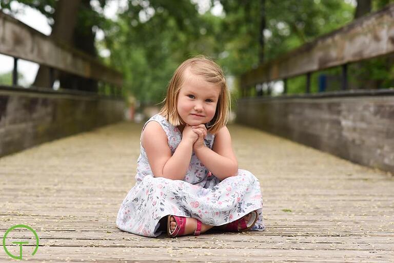 a child poses on Ypsilanti's historic bridge over the huron river for her portrait session