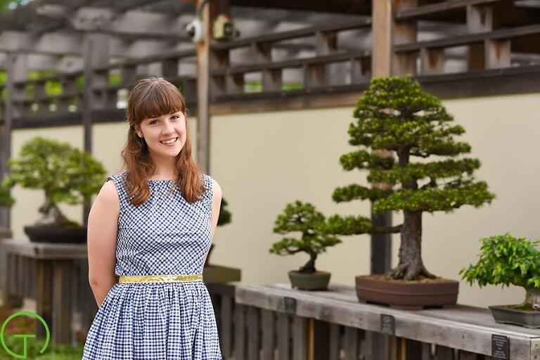 A high school senior poses amongst the bonsai tree collection at Matthaei Botanical Gardens