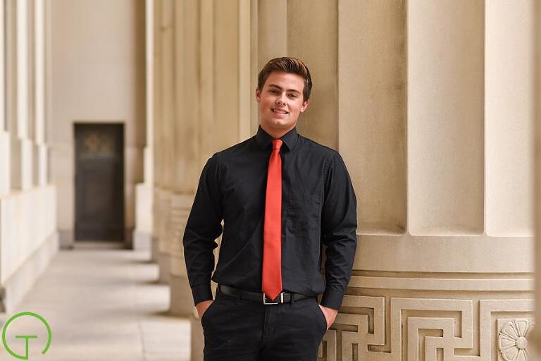 A high school senior poses against the massive pillars of Ann Arbor's Angell Hall for his senior session