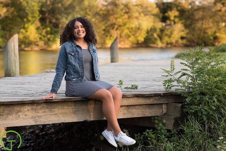 A high school senior poses on a dock near the huron river for her senior portrait
