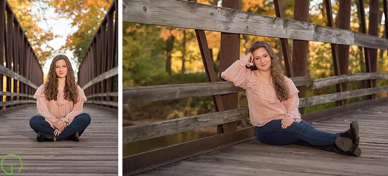 a teenager sits on a wooden bridge with fall color behind her