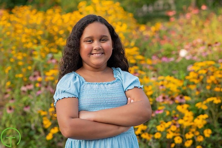 A girl poses in a field of yellow and pink flowers for her Matthaei Botanical Gardens portrait session